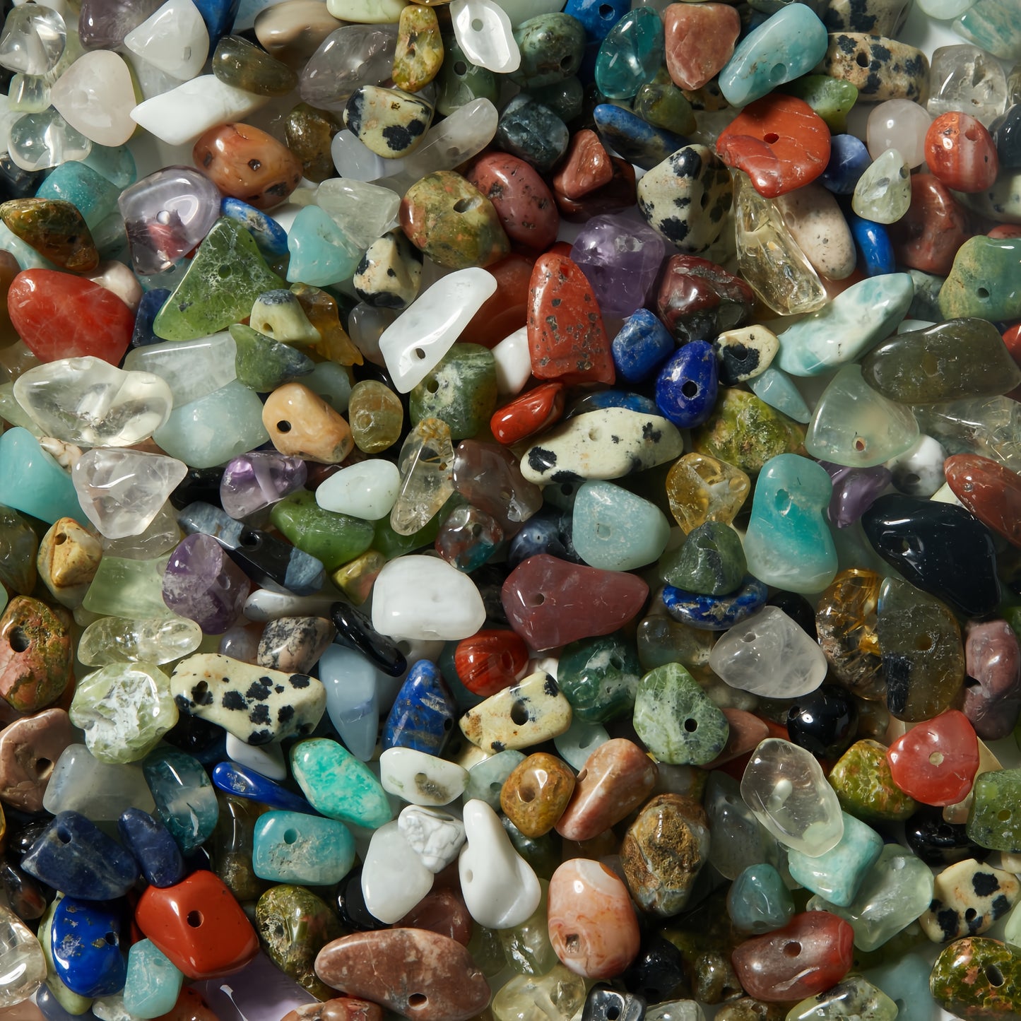 Close-up of assorted natural gemstone chip beads, multicolor polished with drilled holes