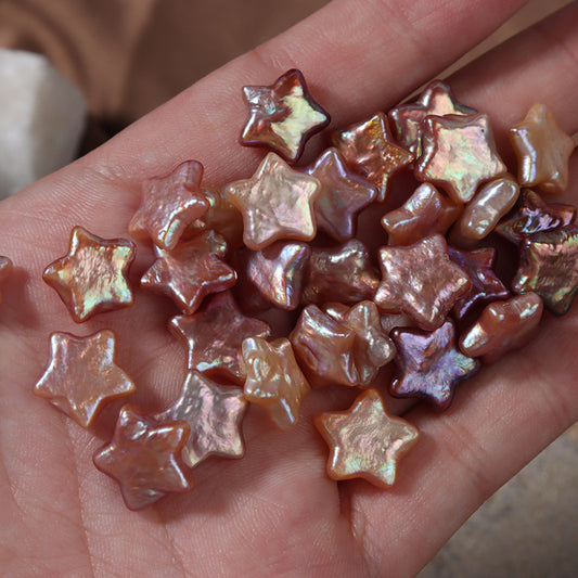 Hand holding several glossy purple and golden-orange star pearls