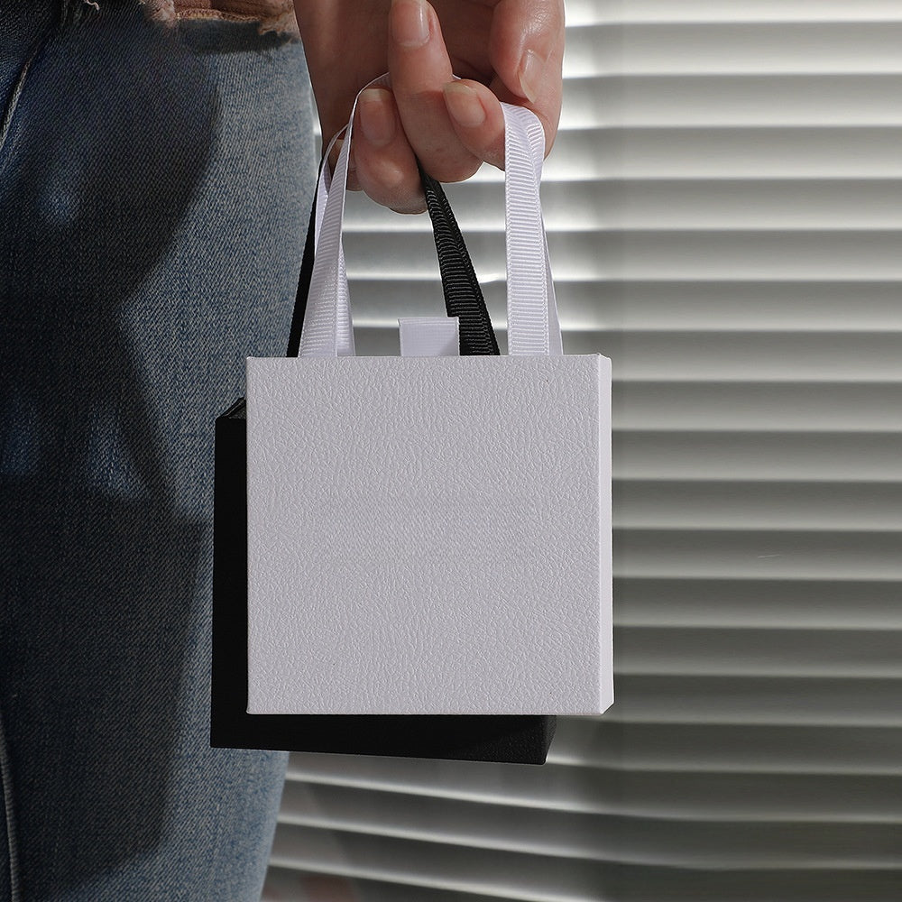 Jewelry drawer gift boxes in white, grey, and black being held in hand