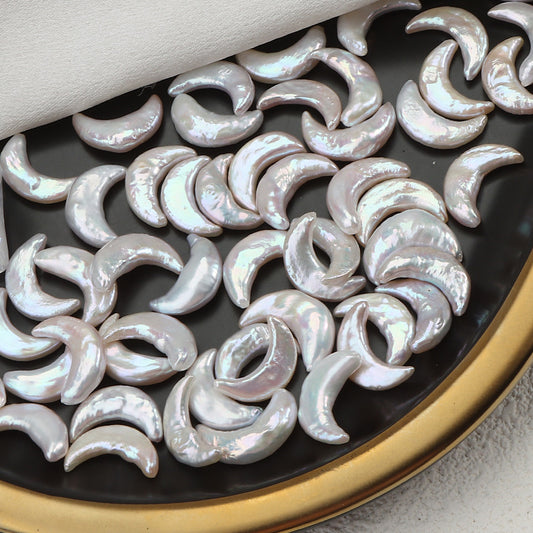 Dozens of white moon-shaped pearls on a black and gold tray