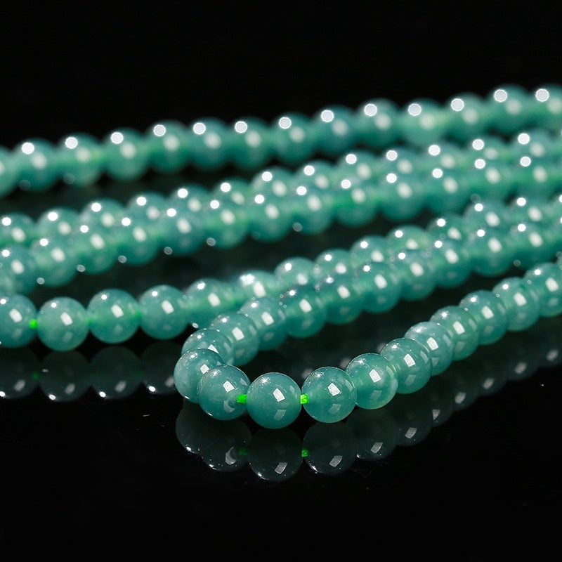 Natural green jadeite gemstone beads shown against black background.