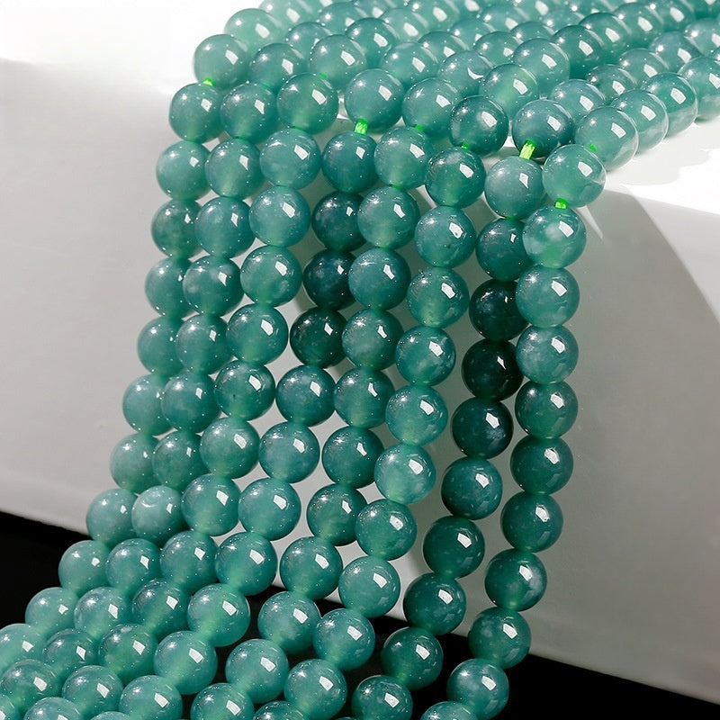 Close-up view of high-grade green jadeite round beads with glossy finish.