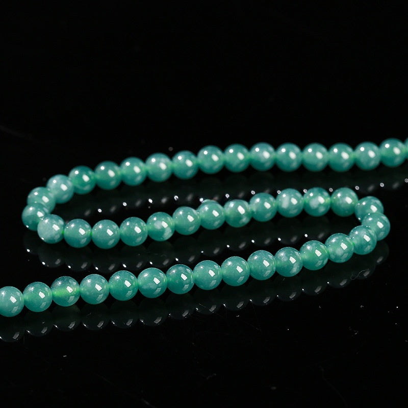 Full strand of natural jadeite round beads neatly arranged for crafting.