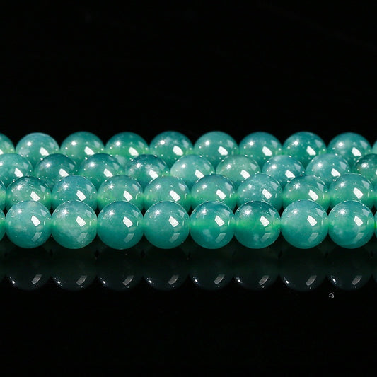 Overview of natural jadeite round beads in translucent green for jewelry making.