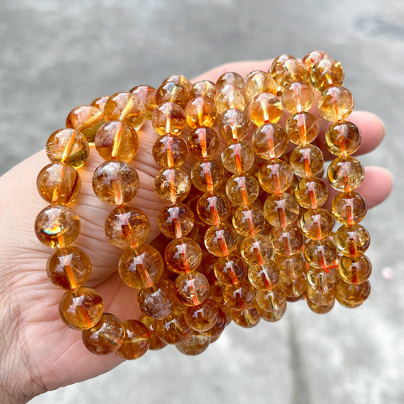 High-grade 7A yellow rutile quartz beads in a handheld close-up view, ideal for jewelry making.