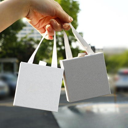 Jewelry drawer gift boxes in white, grey, and black being held in hand