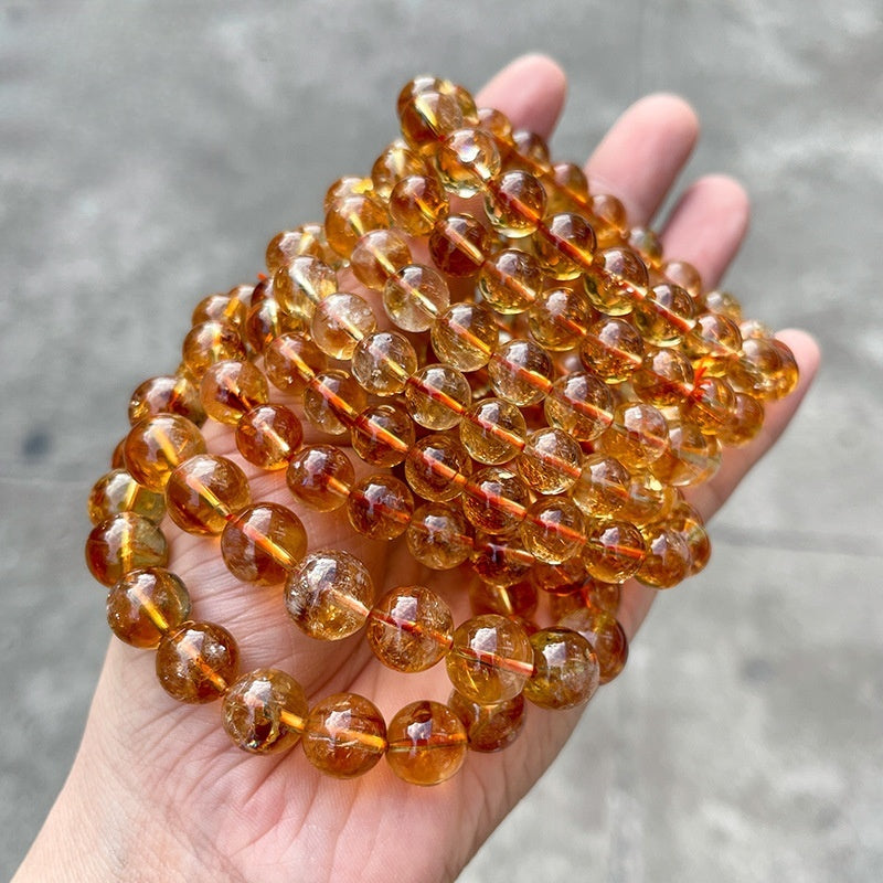 7A natural yellow rutile quartz round beads shown under bright light for clarity and texture.